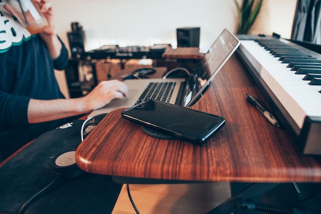 black android smartphone beside macbook and piano